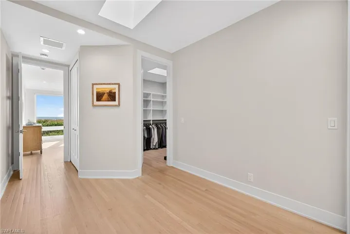 Corridor with a skylight, light wood-style flooring, and recessed lighting