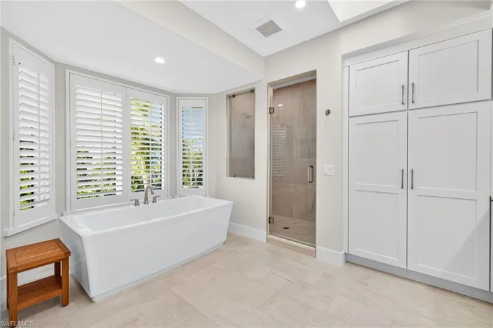 Bathroom with a freestanding tub, a shower stall, recessed lighting, and a skylight