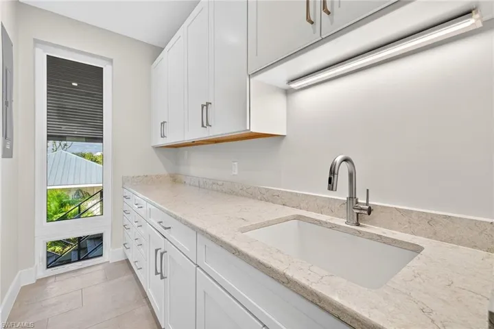 Kitchen with light stone counters, white cabinets, and light tile patterned floors