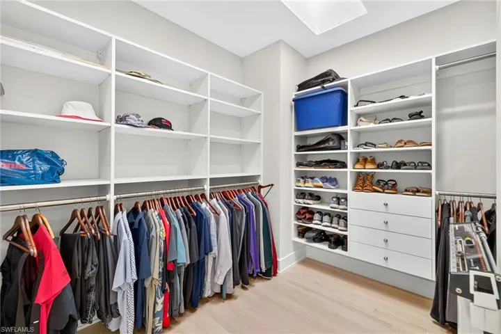 Spacious closet featuring light wood-style flooring and a skylight