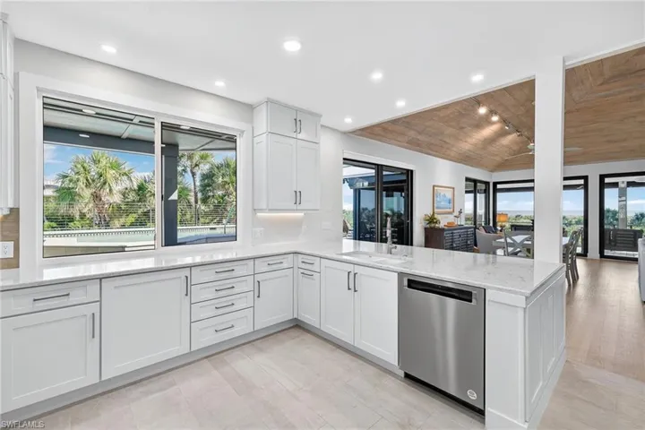 Kitchen featuring wooden ceiling, healthy amount of natural light, stainless steel dishwasher, light stone counters, and a peninsula