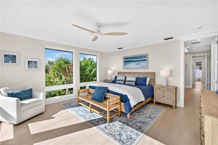 Bedroom with light wood finished floors, ornamental molding, and ceiling fan