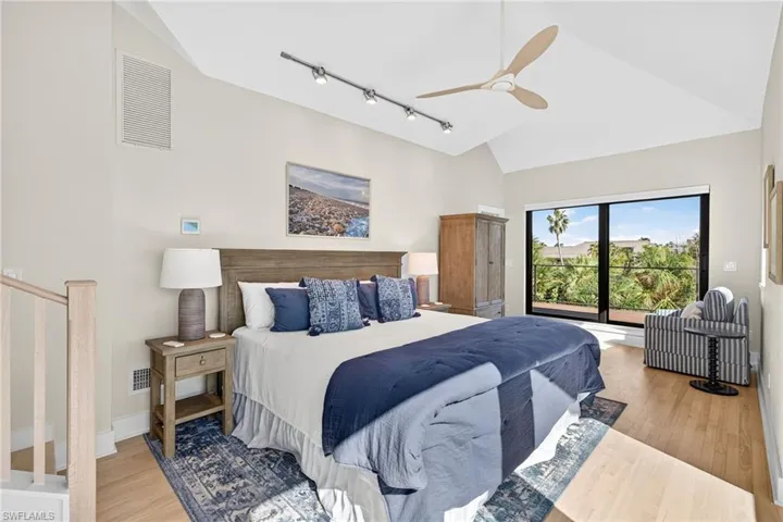 Bedroom with high vaulted ceiling, light wood-style flooring, ceiling fan, and track lighting