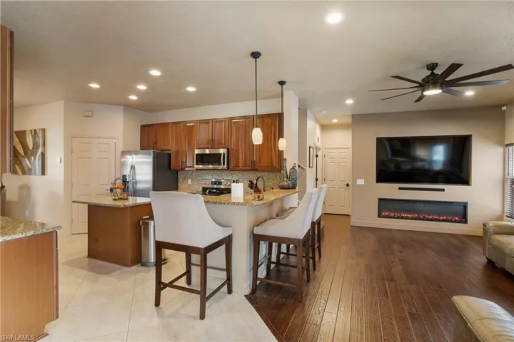 Kitchen featuring appliances with stainless steel finishes, a breakfast bar area, a peninsula, light stone countertops, and pendant lighting