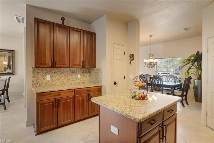 Kitchen featuring a center island, visible vents, brown cabinetry, and decorative light fixtures