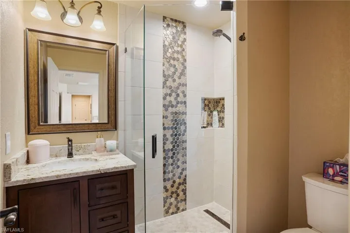 Full bathroom with a stall shower, visible vents, vanity, and toilet