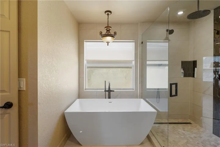 Full bath with a textured wall, a soaking tub, and a shower stall