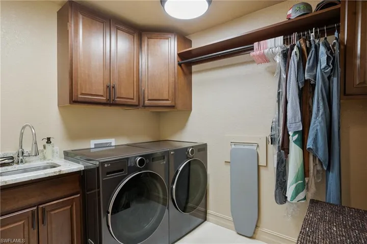 Laundry room featuring cabinet space, a sink, washer and clothes dryer, and baseboards