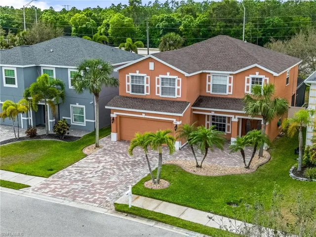 View of front of home featuring an attached garage, roof with shingles, decorative driveway, stucco siding, and a front yard
