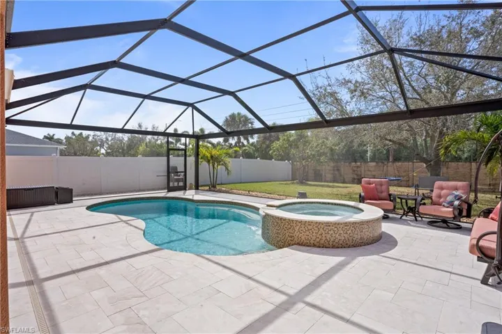 View of swimming pool featuring a lanai, a patio area, a fenced backyard, and a pool with connected hot tub