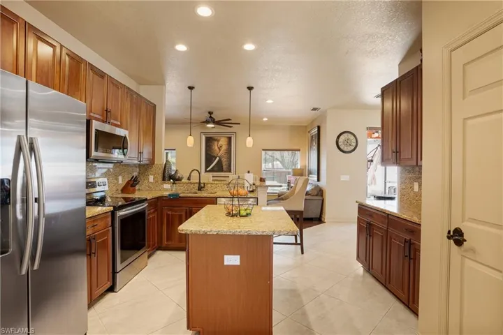 Kitchen featuring a sink, hanging light fixtures, appliances with stainless steel finishes, a center island, and tasteful backsplash