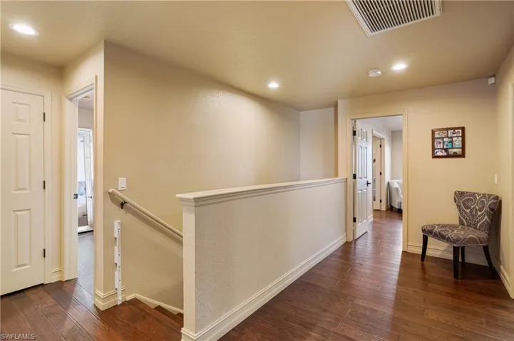 Corridor featuring recessed lighting, an upstairs landing, visible vents, baseboards, and dark wood-style floors