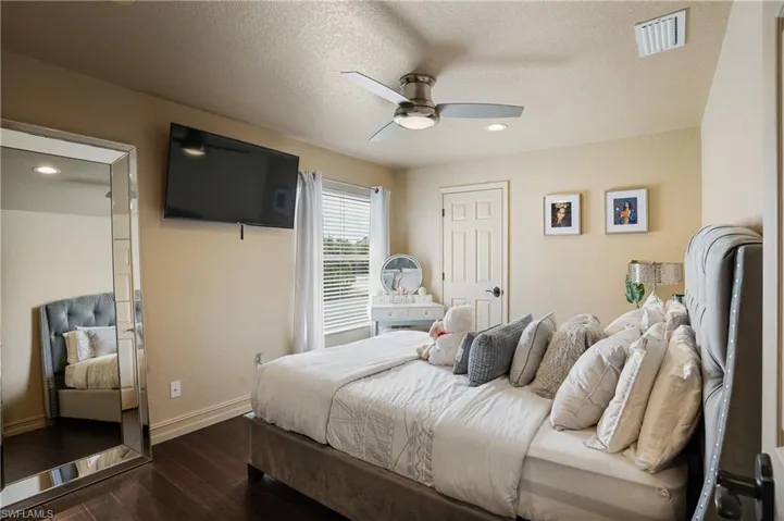 Bedroom featuring dark wood-style flooring, visible vents, ceiling fan, a textured ceiling, and baseboards