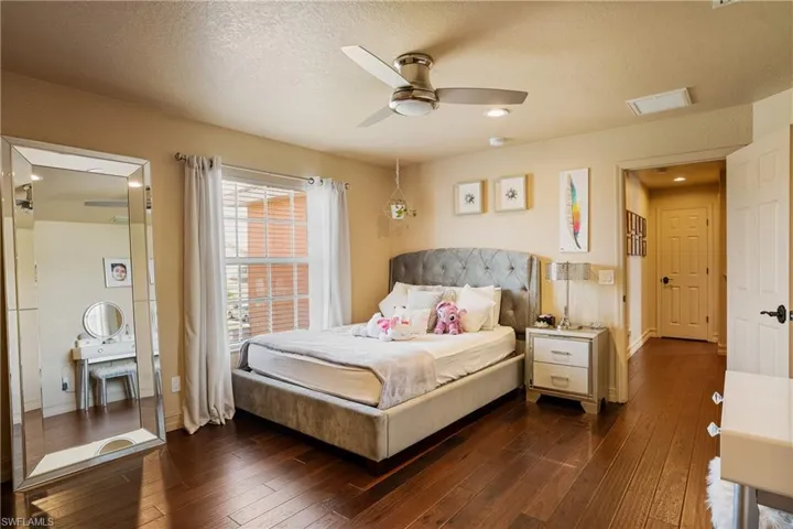 Bedroom with visible vents, baseboards, dark wood-style floors, ceiling fan, and a textured ceiling