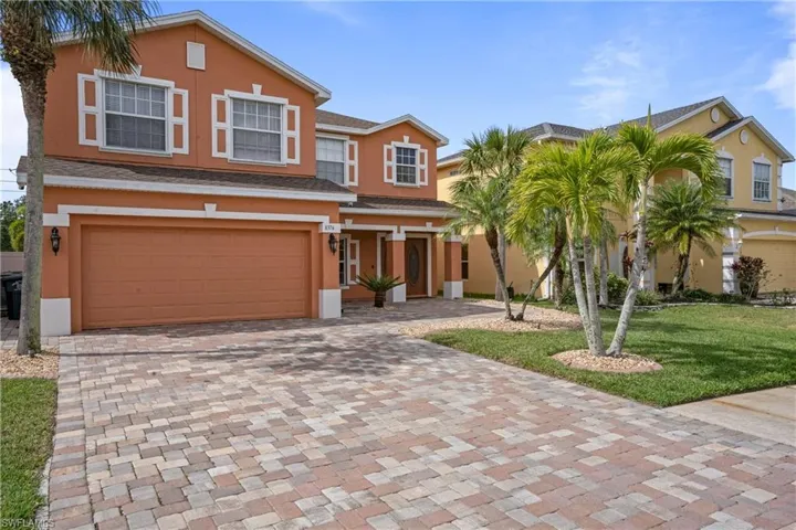 View of front of property with a garage, decorative driveway, a front yard, and stucco siding
