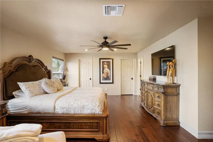 Bedroom featuring baseboards, visible vents, ceiling fan, and dark wood-type flooring