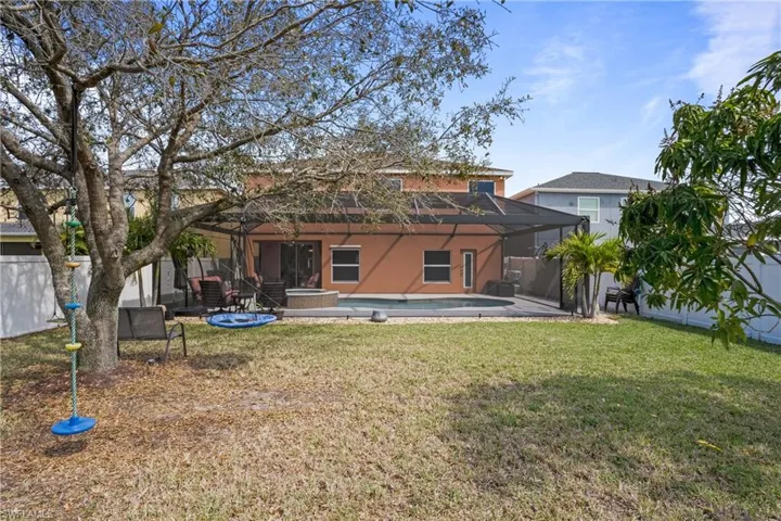 Rear view of house with a fenced in pool, glass enclosure, a lawn, and stucco siding