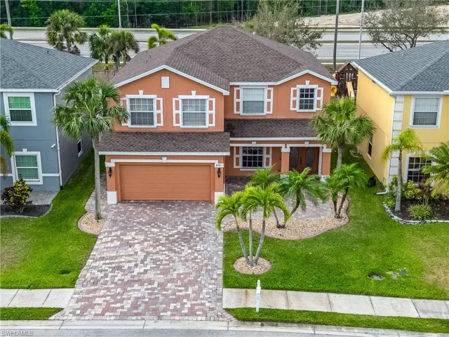 Traditional-style house with a garage, roof with shingles, decorative driveway, and stucco siding