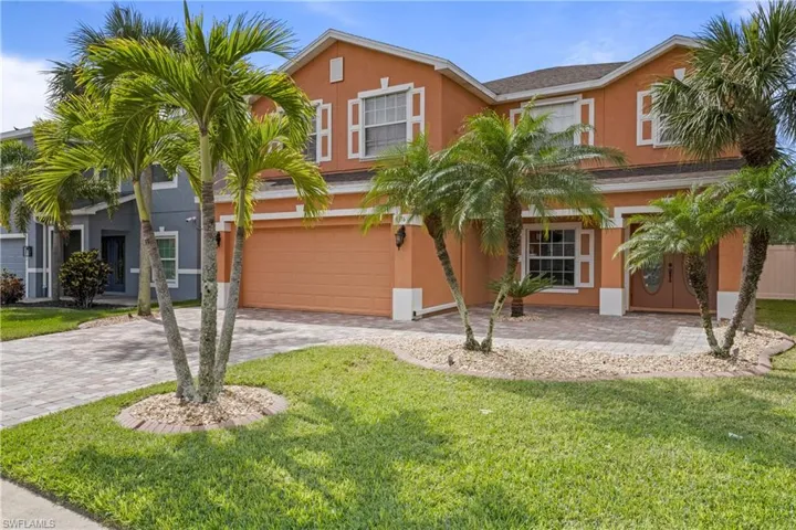 View of front of property featuring an attached garage, decorative driveway, a front yard, and stucco siding