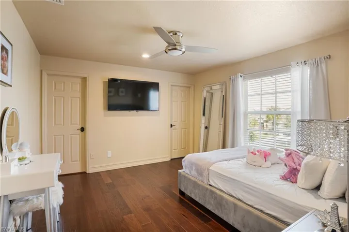 Bedroom featuring dark wood-style floors, baseboards, and a ceiling fan