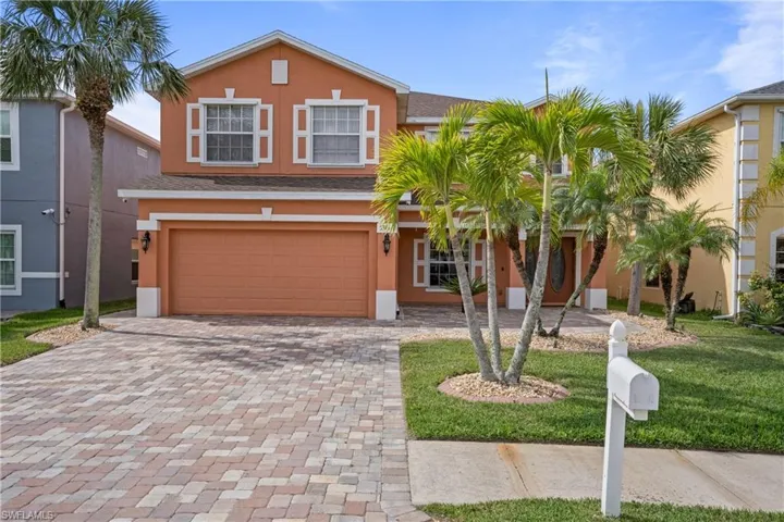 View of front of property with a garage, decorative driveway, a front lawn, and stucco siding