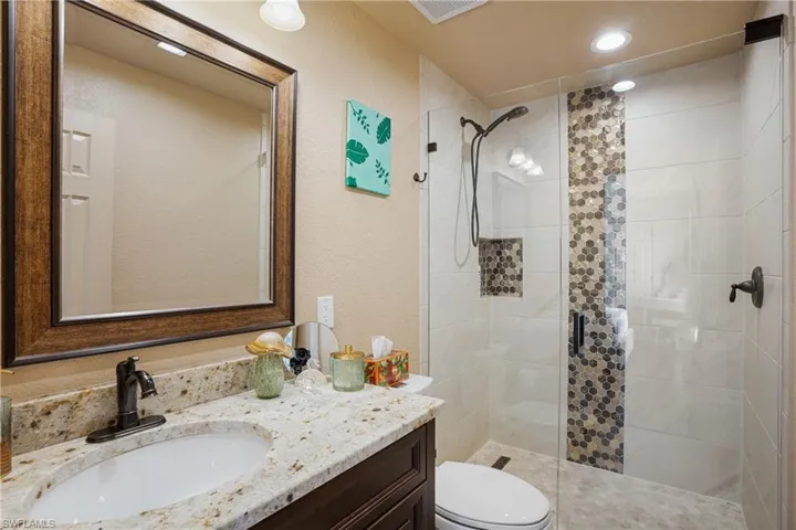 Bathroom with visible vents, tiled shower, vanity, and toilet