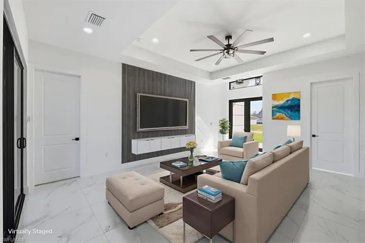 Living room featuring a tray ceiling, light marble finish flooring, ceiling fan, and recessed lighting