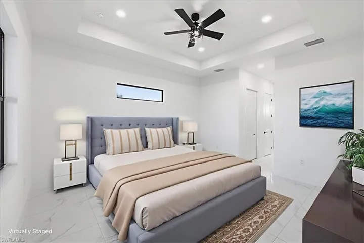 Bedroom featuring a tray ceiling, light marble finish floors, recessed lighting, and a ceiling fan