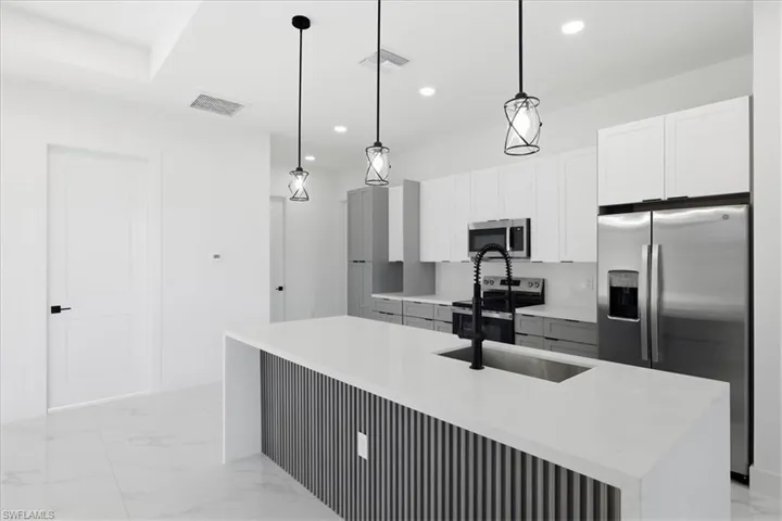 Kitchen featuring stainless steel appliances, light marble finish flooring, light stone countertops, white cabinets, and recessed lighting