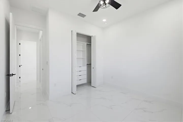 Unfurnished bedroom featuring light marble finish floors, ceiling fan, a closet, and recessed lighting