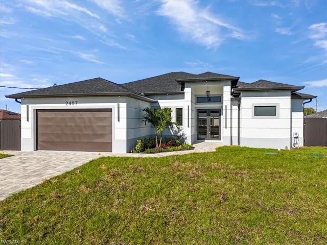 Prairie-style house featuring french doors, decorative driveway, stucco siding, and an attached garage