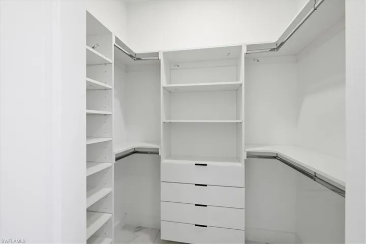 Walk in closet featuring light marble finish floors
