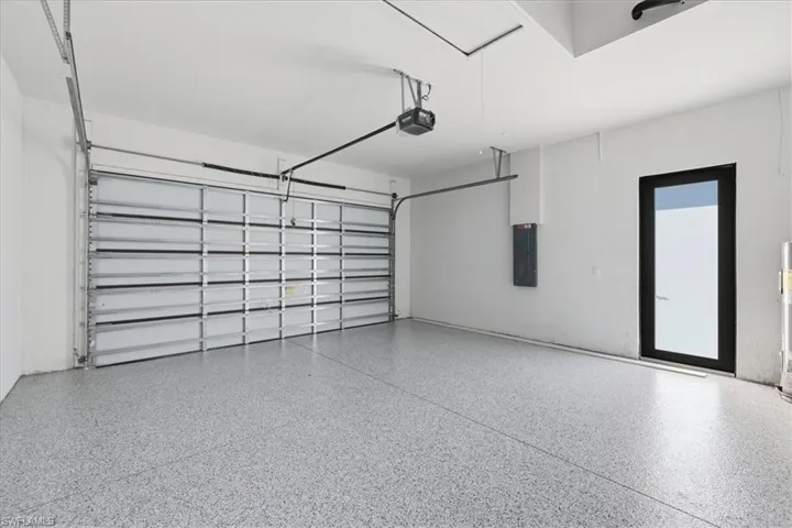 Garage with electric panel, a garage door opener, and water heater