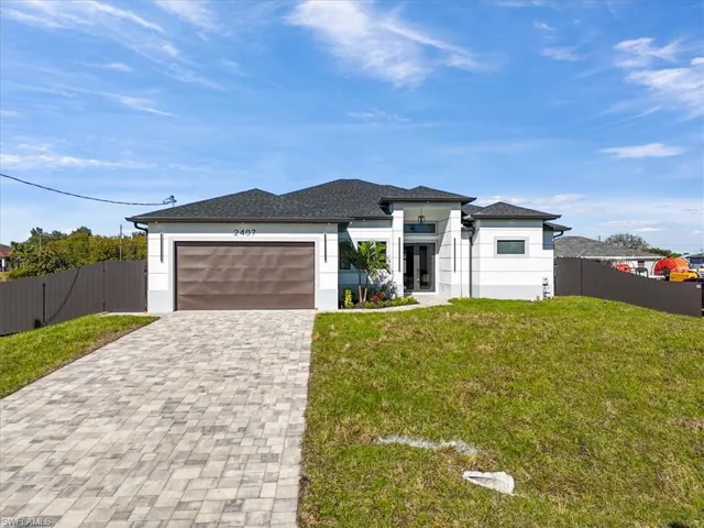 Prairie-style home with decorative driveway, an attached garage, stucco siding, and roof with shingles