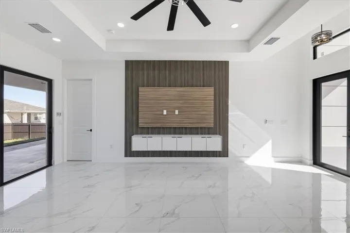 Unfurnished living room with light marble finish flooring, a tray ceiling, and recessed lighting