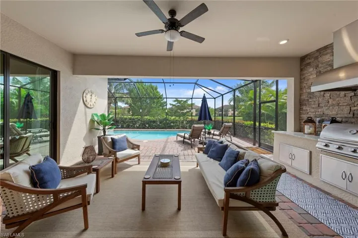 View of patio featuring a sunroom, exterior kitchen, an outdoor hangout area, a ceiling fan, and glass enclosure