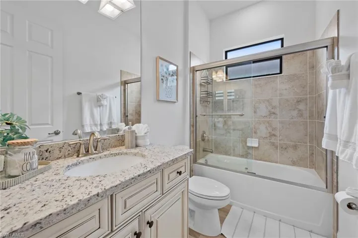 Bathroom with bath / shower combo with glass door and vanity