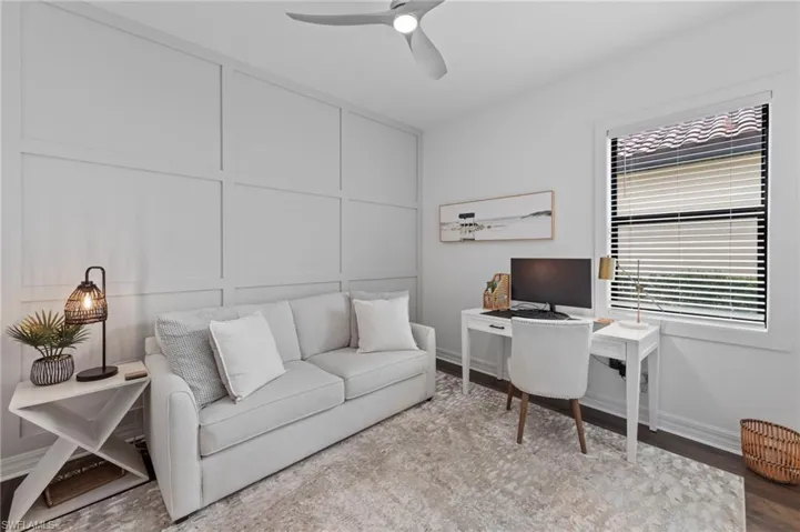 Office space with wood finished floors, a ceiling fan, and a decorative wall