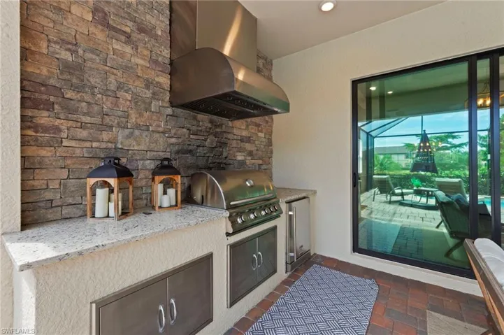 Kitchen featuring island range hood, light stone countertops, stainless steel fridge, and recessed lighting