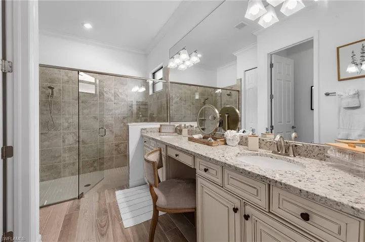 Bathroom featuring vanity, a stall shower, light wood finished floors, and crown molding