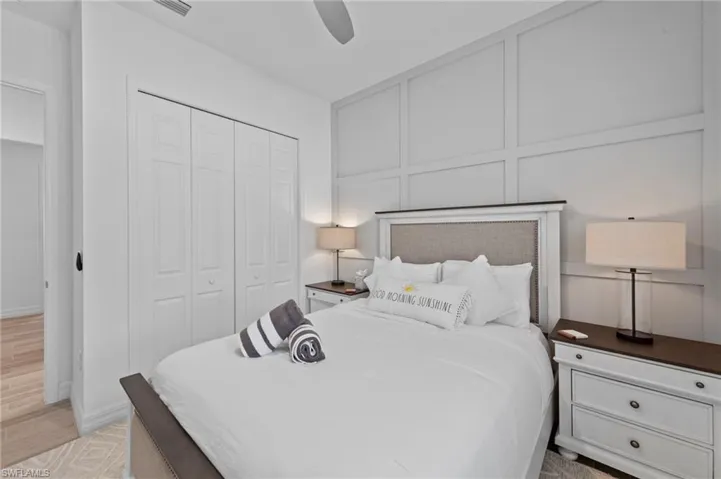 Bedroom with a decorative wall, a closet, ceiling fan, and light wood-style floors