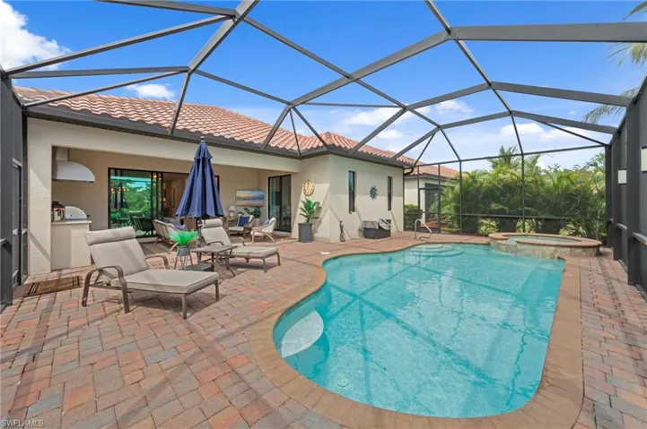 View of pool featuring a sunroom, a patio area, a pool with connected hot tub, and glass enclosure