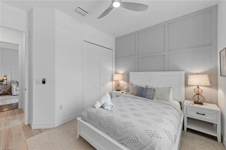 Bedroom with a decorative wall, a ceiling fan, a closet, and light wood-style floors