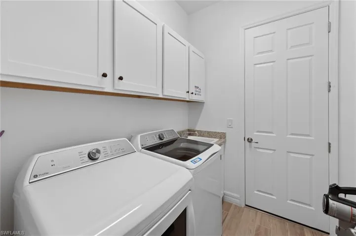 Laundry area with light wood-style flooring and washing machine and clothes dryer