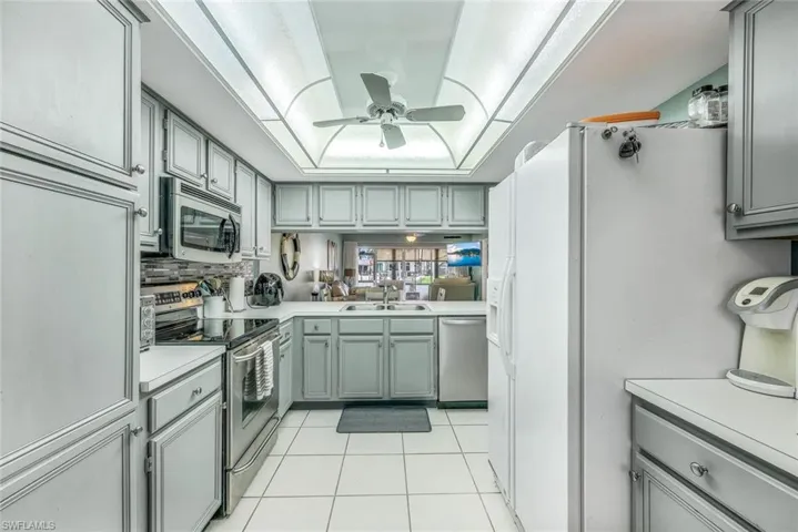 Kitchen with ceiling fan, light tile flooring, gray cabinetry, sink, and appliances with stainless steel finishes