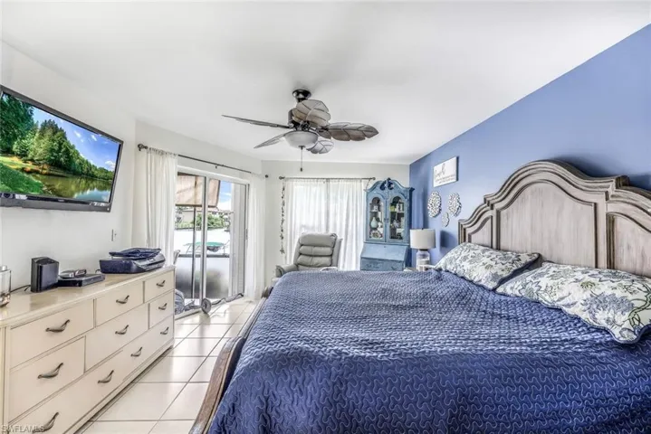 Bedroom featuring ceiling fan, light tile flooring, and access to exterior