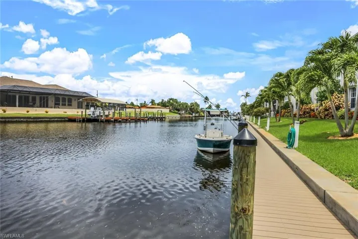 View of dock with a water view and a lawn