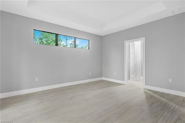 Spare room featuring a tray ceiling and light wood-type flooring