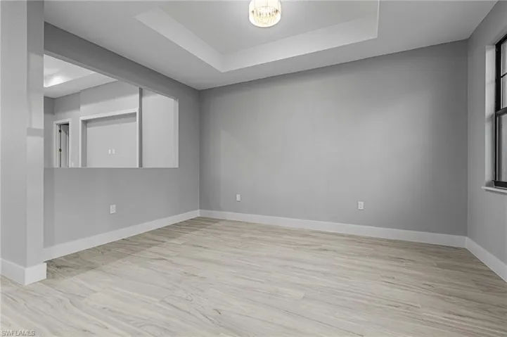 Empty room with a tray ceiling and light wood finished floors