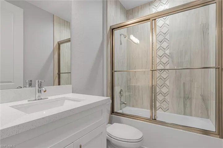 Bathroom with vanity and bath / shower combo with glass door
